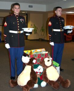 Two men standing beside a pile of teddy bears